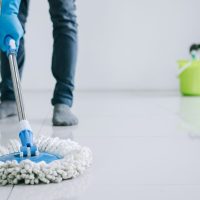 Husband housekeeping and cleaning concept, Happy young man in blue rubber gloves wiping dust using mop while cleaning on floor at home.